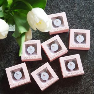 A selection of See Beauty false eyelashes in a pink box and on a dark background